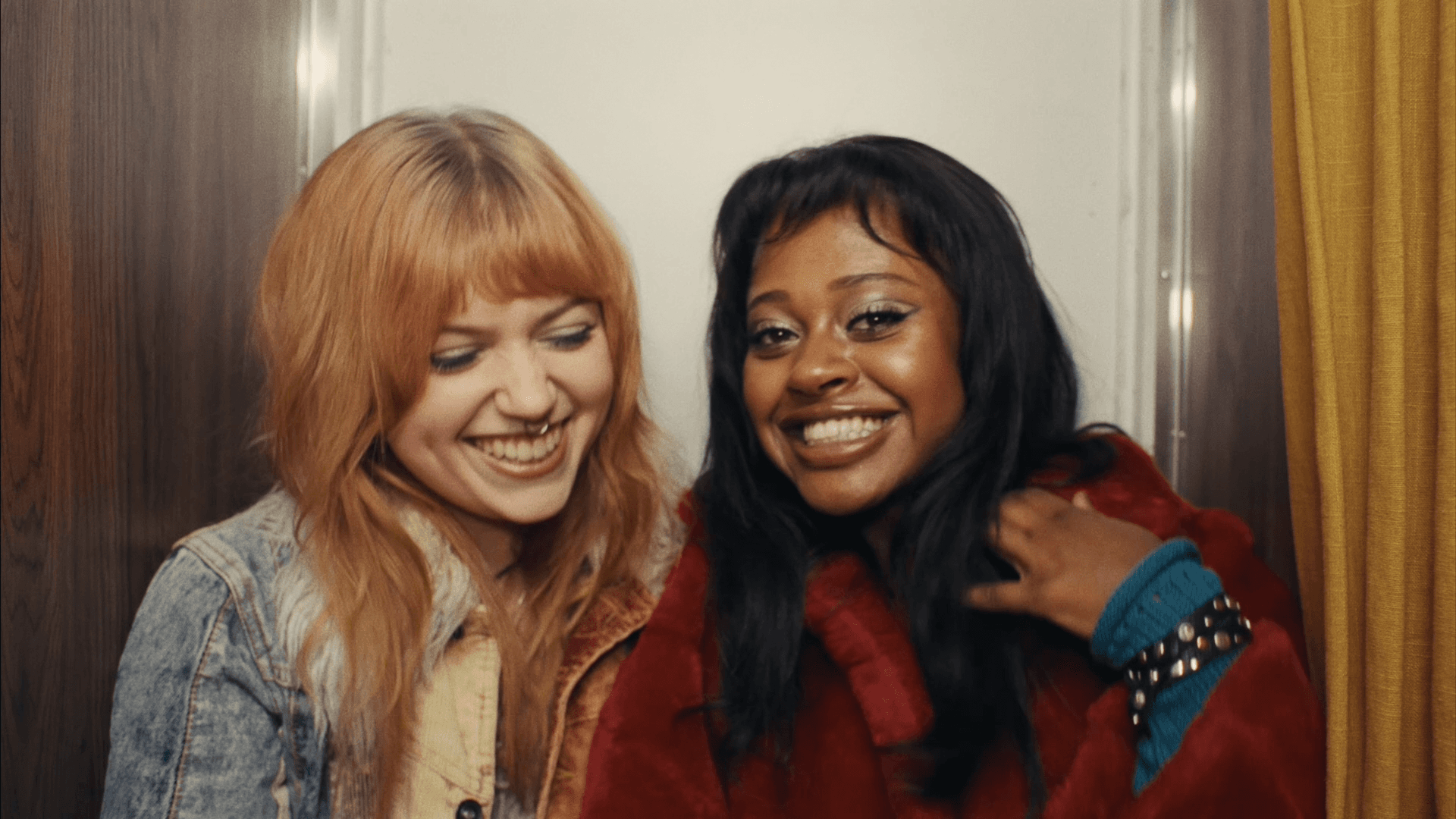 Two young women smiling together indoors.