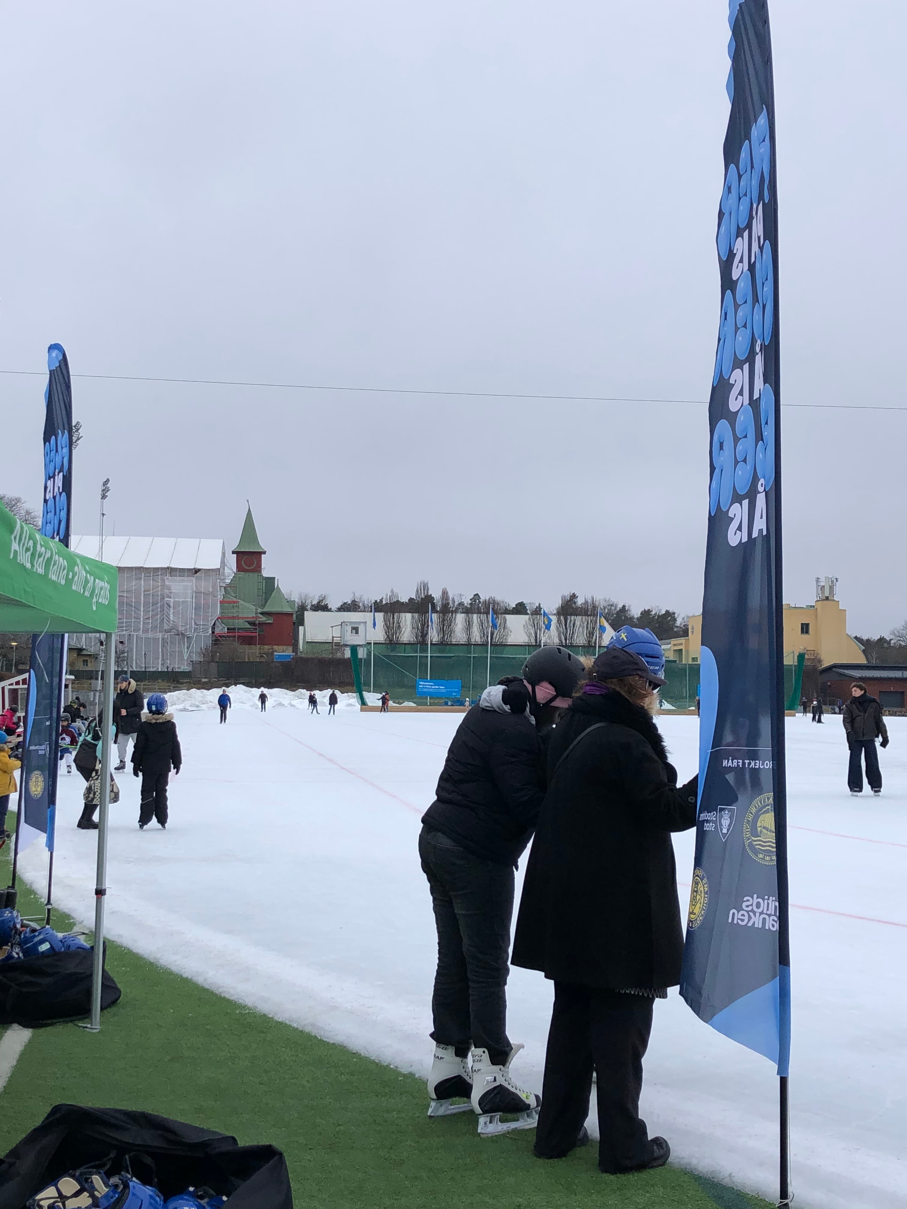 People in front of an outdoors hockey rink.